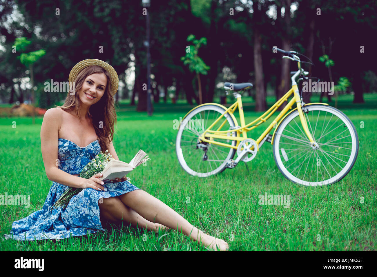 Bella giovane donna ritratto la lettura di un libro con la bicicletta nel parco. Foto Stock