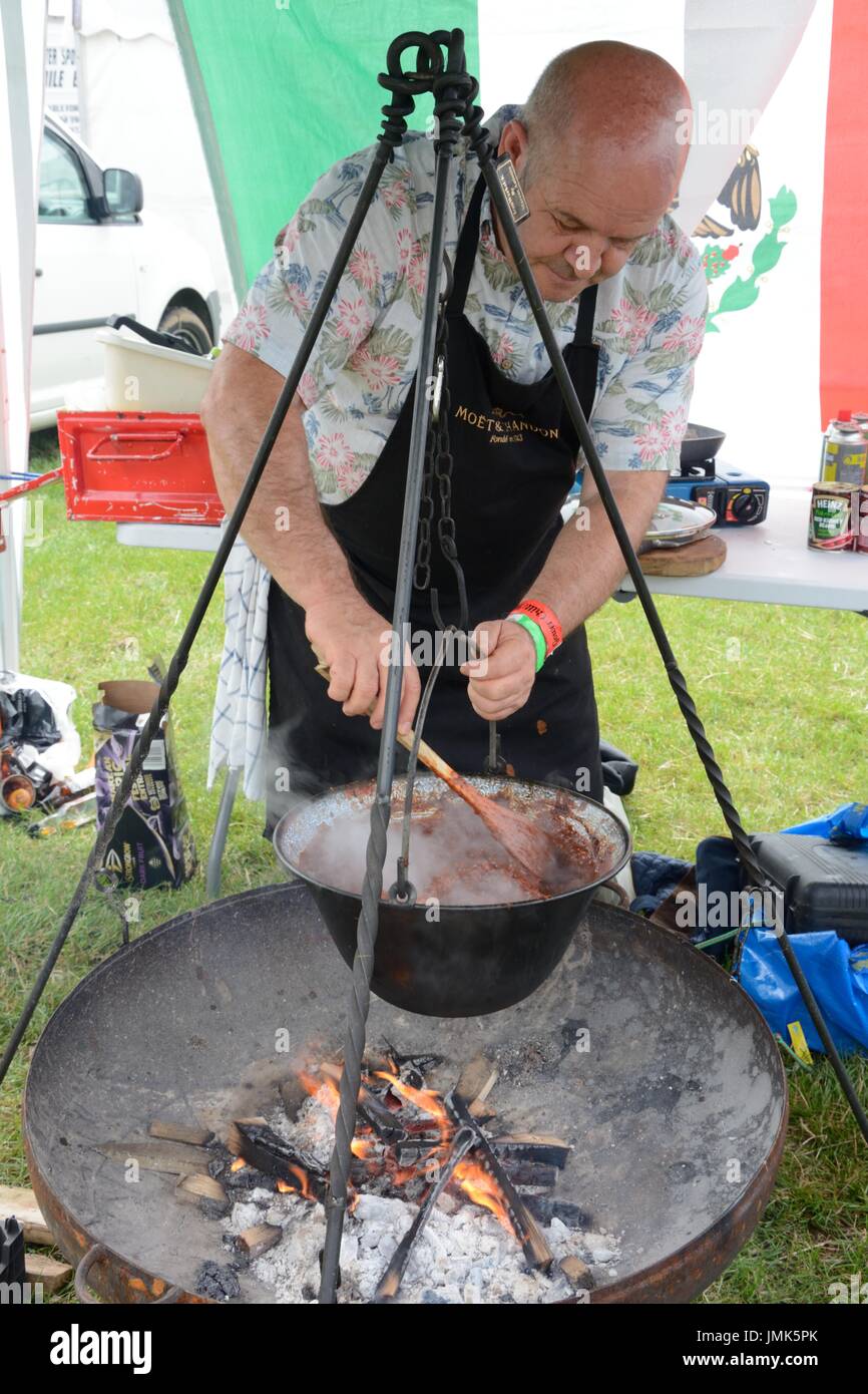 Un uomo di carbone da coke chili con carne oltre ad aprire il fuoco in una ghisa pentola Gower chili Festival Glamorgan Foto Stock