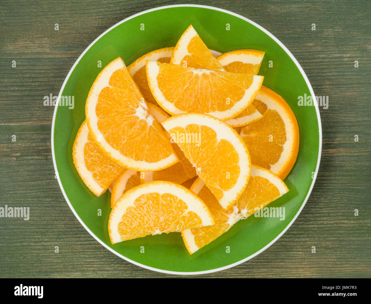 Taglio fresco succose fette di arancio o segmenti contro un verde sullo sfondo di legno Foto Stock