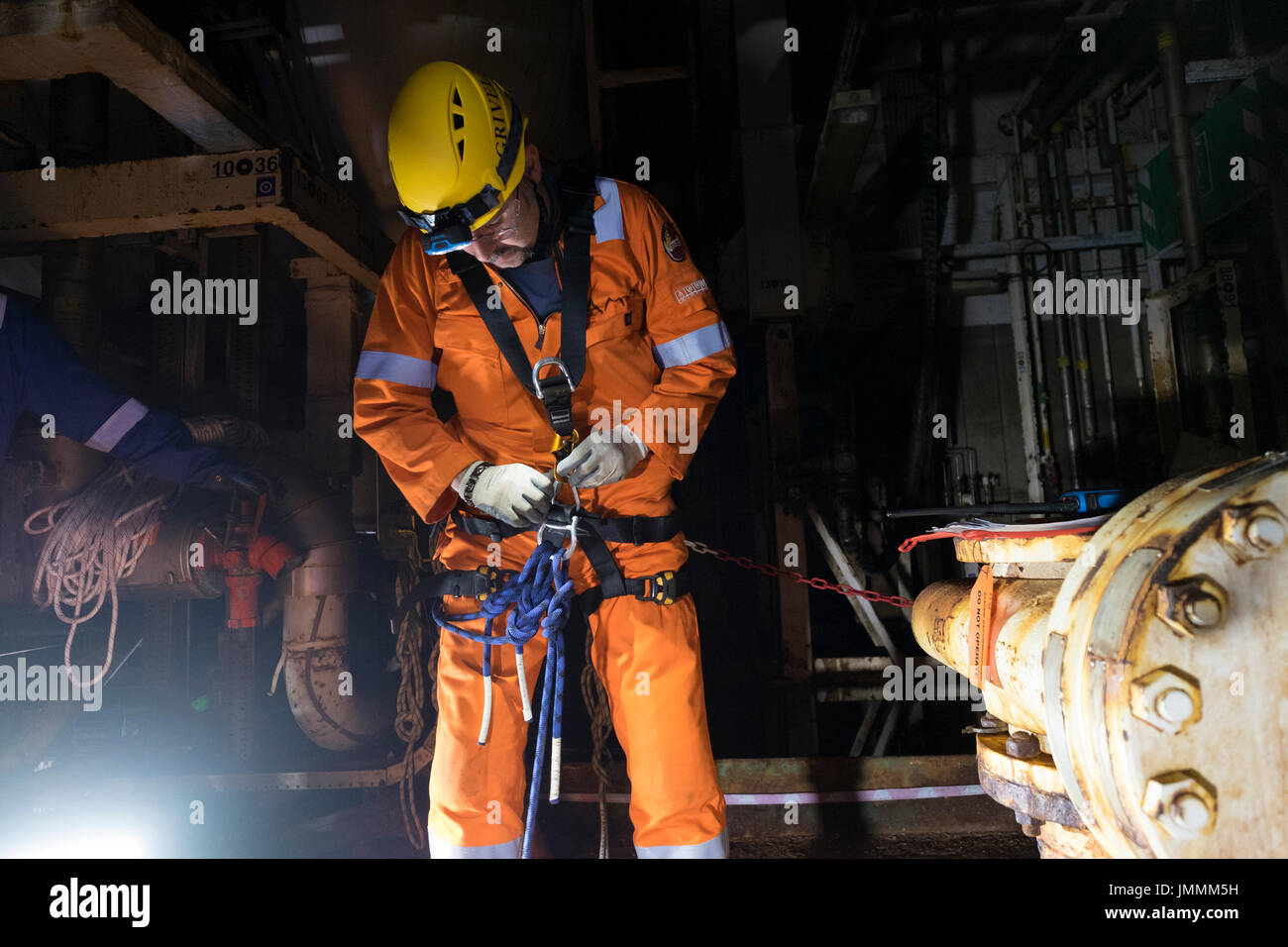 Una corda industriale tecnico accesso impostazione di cablaggio, sul petrolio del Mare del Nord e l'installazione di gas indossando tute arancioni. Credito: LEE RAMSDEN / ALAMY Foto Stock