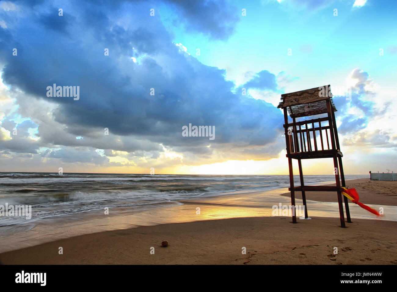 Paesaggio di spiaggia con mare mosso e il legno della torre di vedetta al tramonto. Foto Stock