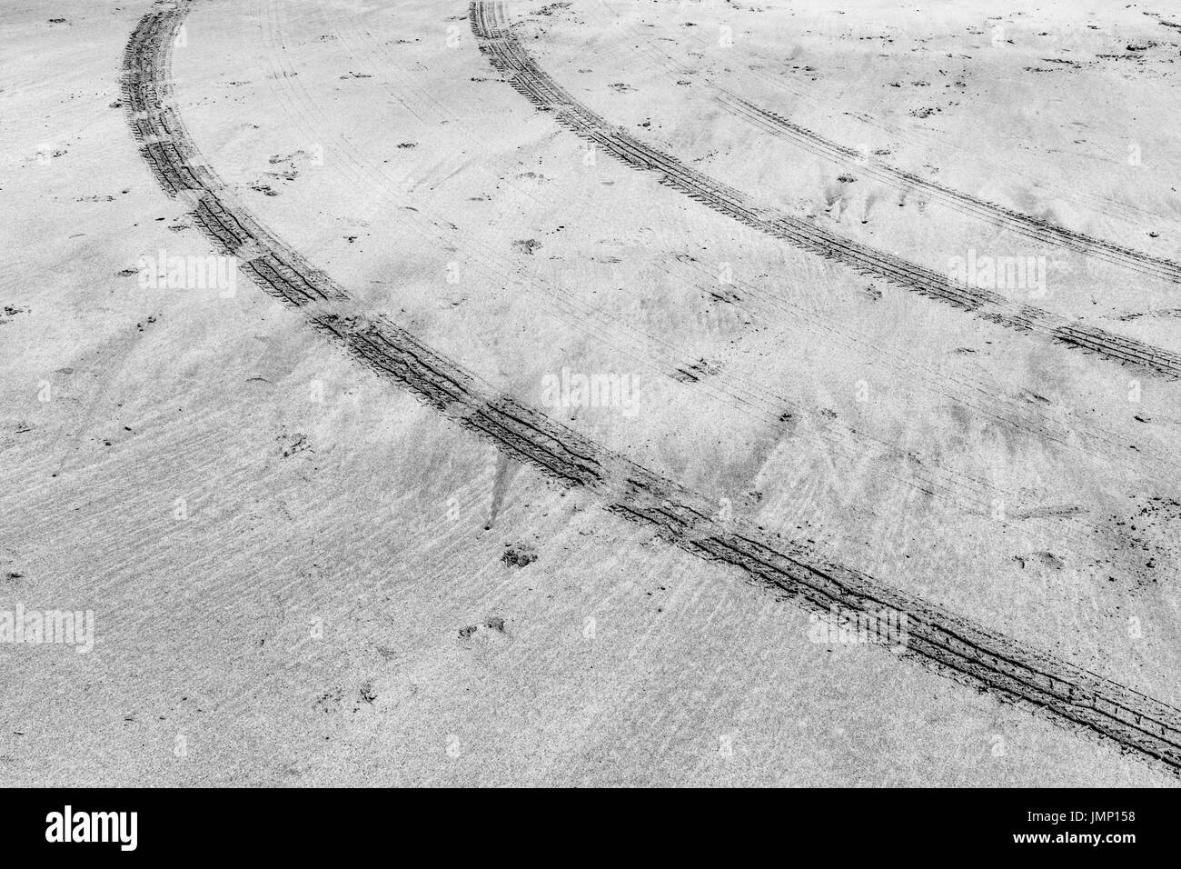 Immagine in bianco e nero di forma curva/ curvando tracce di pneumatici in umidità spiaggia di sabbia in Cornovaglia, UK. Piste curve, curvando tracce di pneumatici. Foto Stock