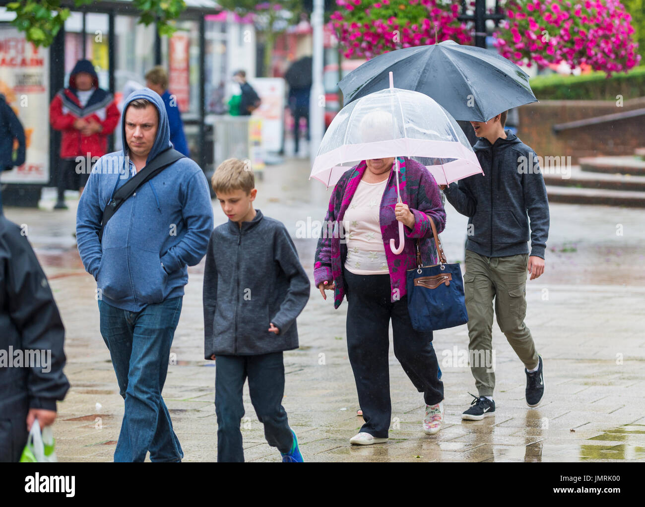 Famiglia camminando sotto la pioggia ombrelli azienda in un centro commerciale. Foto Stock