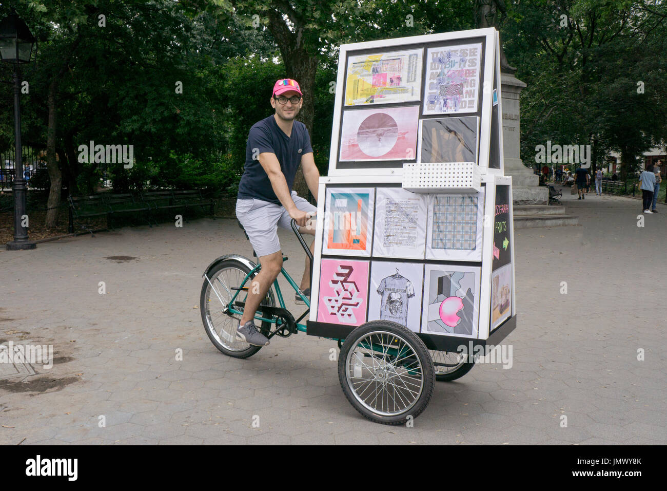 Un bagno turco artista americano vendendo le sue stampe e t shirts da una a tre ruote di bicicletta in Washington Square Park in Greenwich Village. Foto Stock