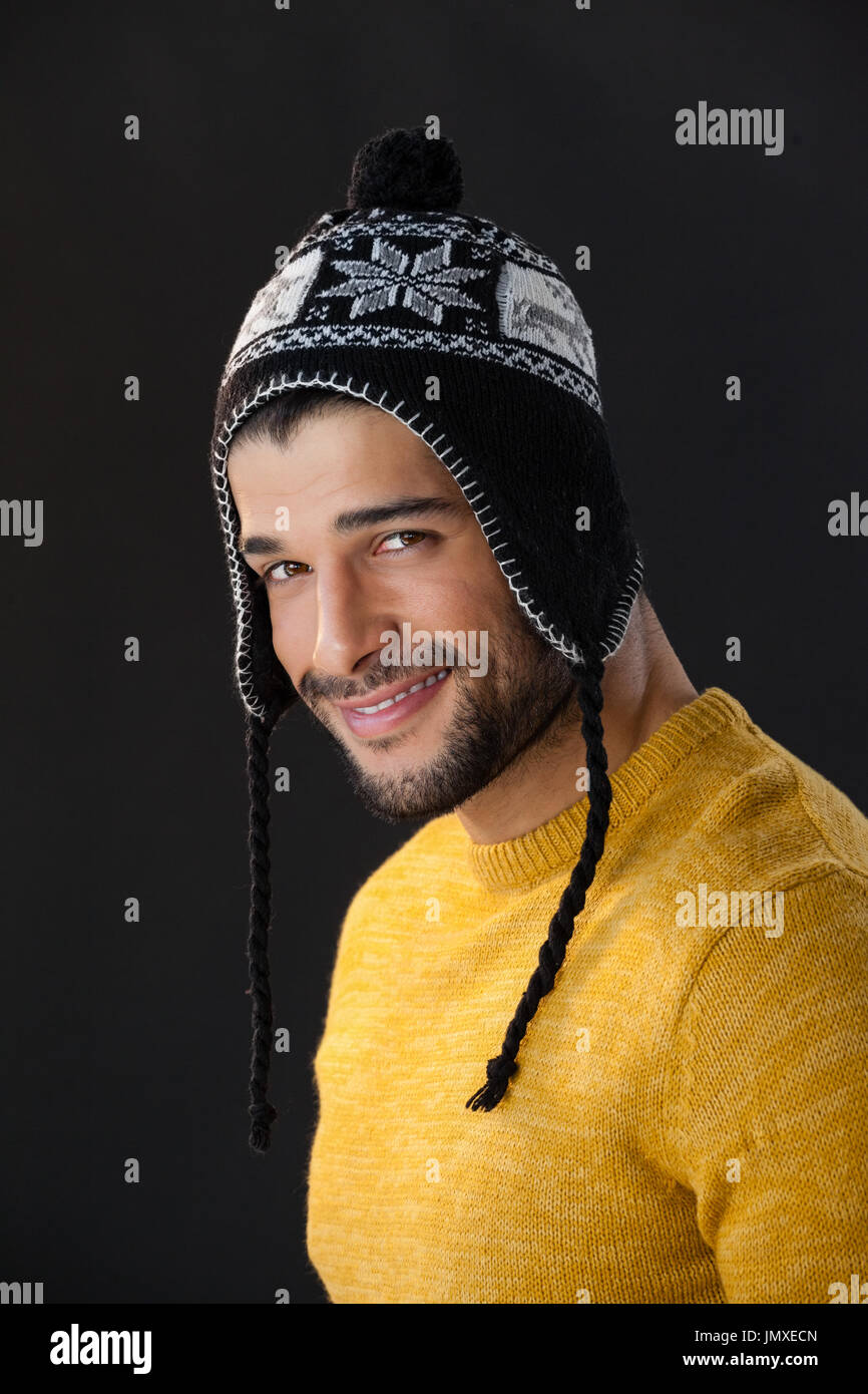 Ritratto di uomo sorridente in wooly hat su sfondo nero Foto Stock