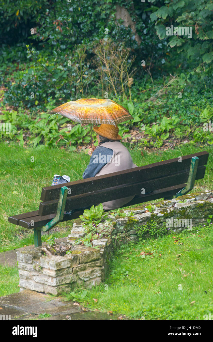 Bournemouth Dorset, Regno Unito. 29 Luglio, 2017. Regno Unito: meteo la pioggia non si ferma questa donna seduta in un parco sotto il suo ombrello per andare a mangiare qualcosa a Robert Louis Stevenson gardens Skerryvore in Westbourne, Bournemouth. Credito: Carolyn Jenkins/Alamy Live News Foto Stock
