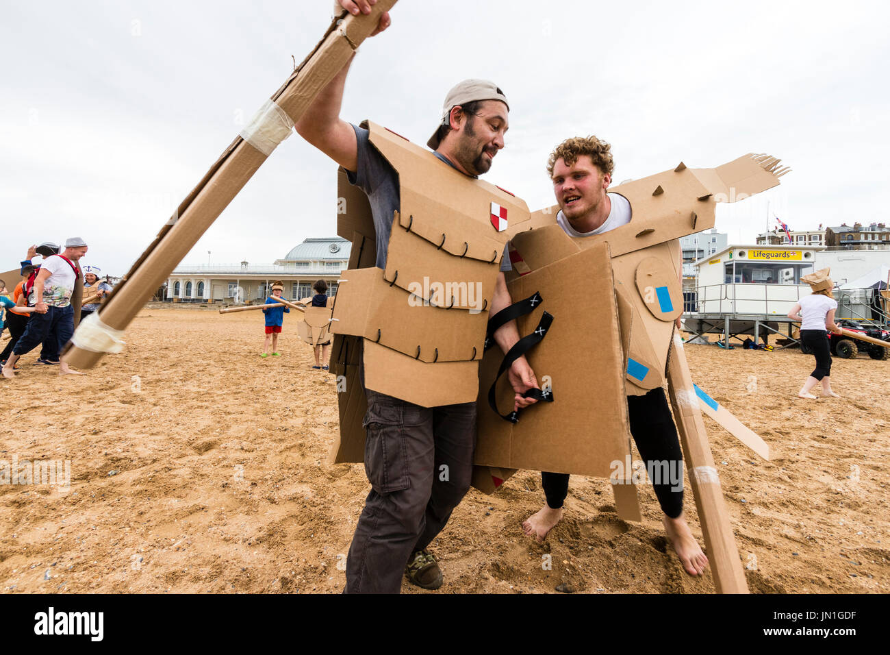 Evento Cardboardia con gli adulti e i bambini vestiti da cavalieri  medievali combattimenti ogni altro sulla spiaggia durante il festival di  Ramsgate. Vestito di corazza di cartone e cartone dimaneggio armi Foto