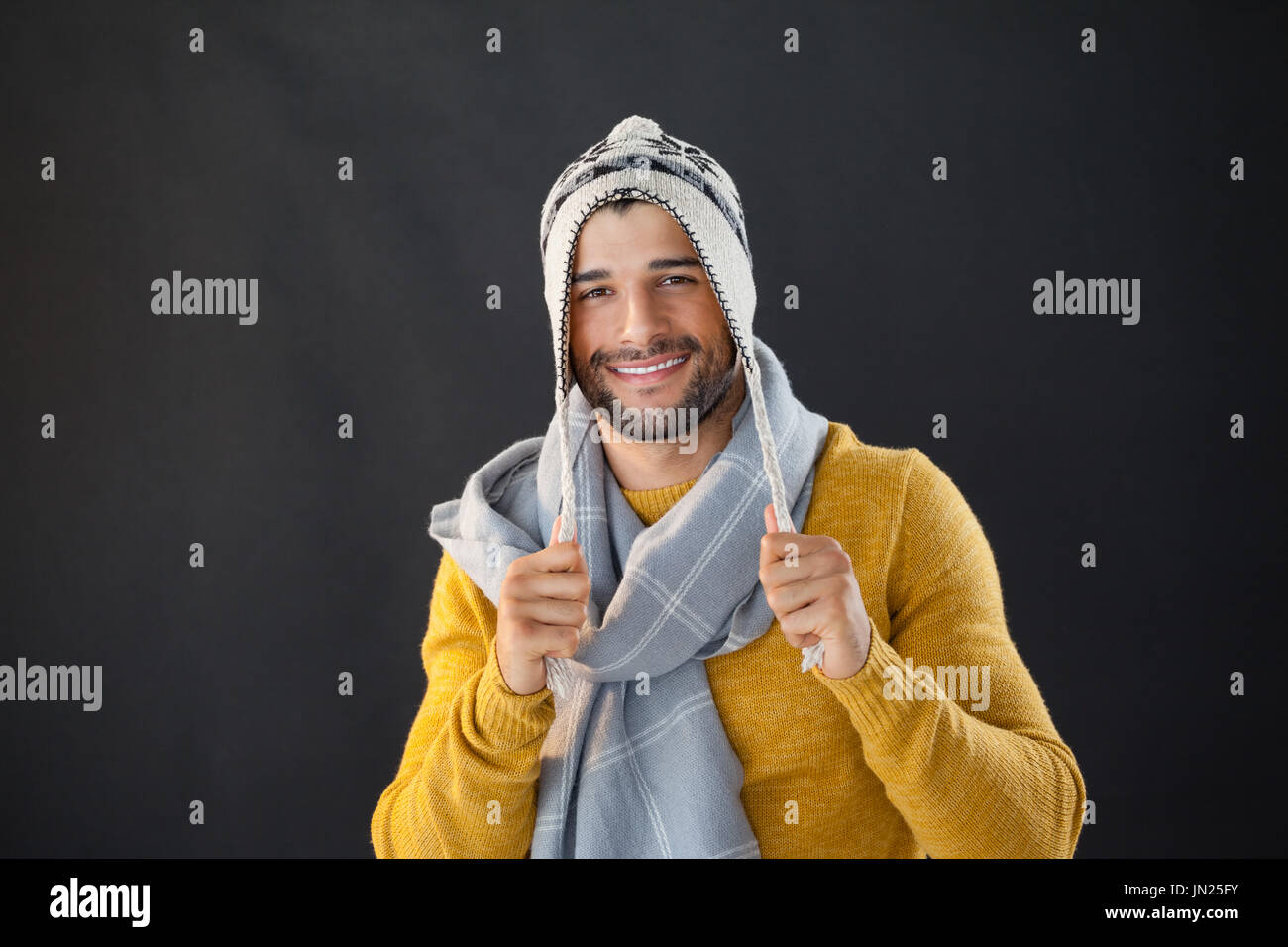 Ritratto di uomo sorridente holding wooly hat su sfondo nero Foto Stock