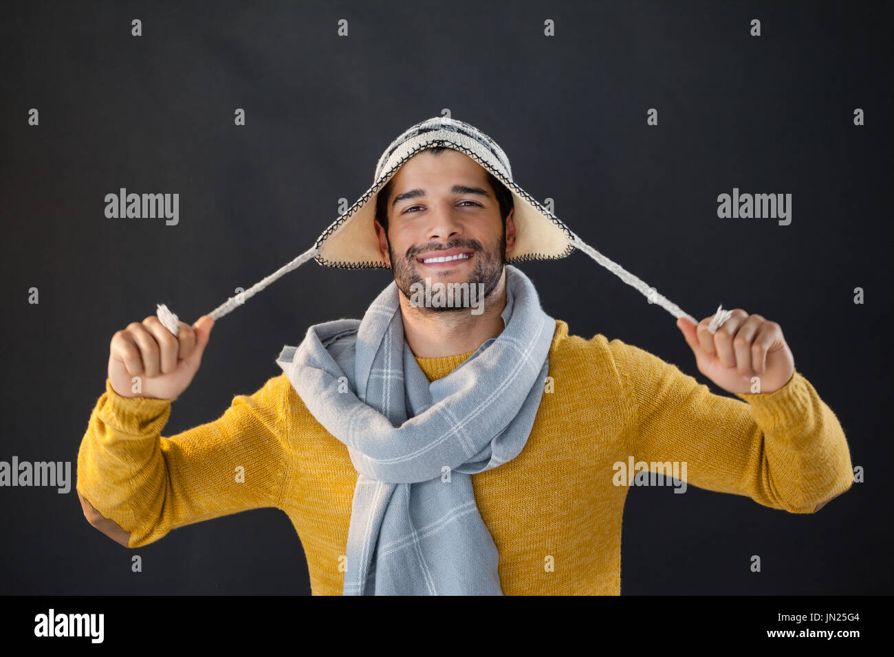 Ritratto di uomo sorridente holding wooly hat su sfondo nero Foto Stock