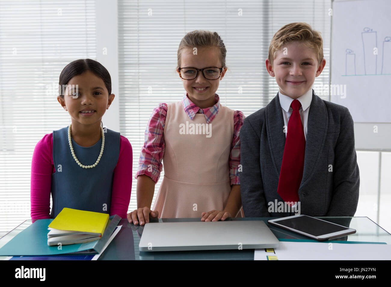 Ritratto di bambini come business executive sorridere mentre in piedi in ufficio Foto Stock