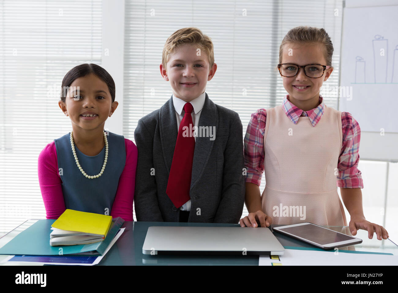 Ritratto di bambini come business executive sorridere mentre in piedi in ufficio Foto Stock