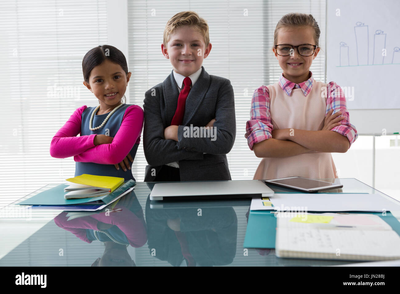 Ritratto di bambini come business executive sorridere mentre in piedi in ufficio Foto Stock