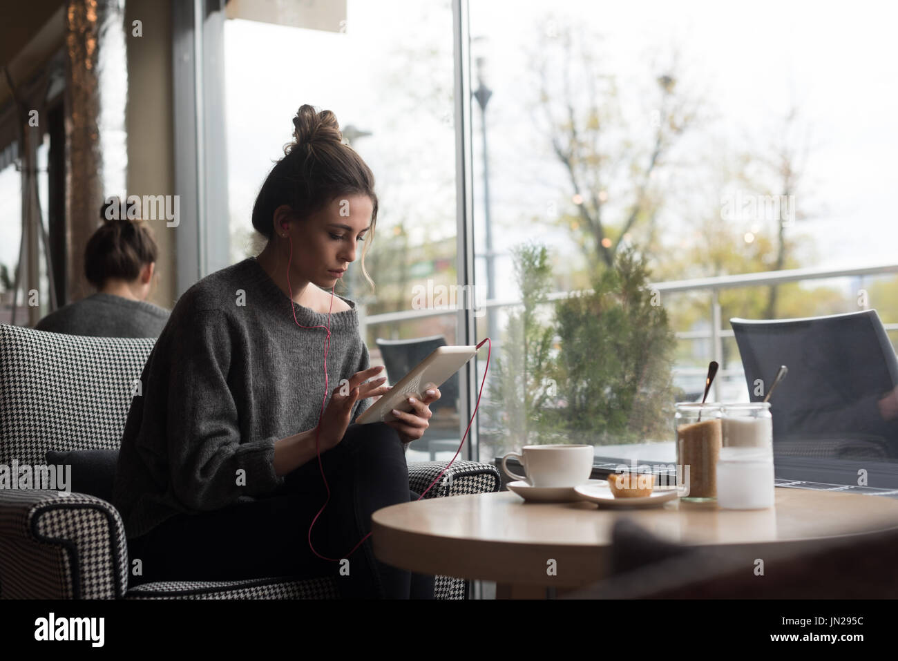 Donna con tavoletta digitale mentre è seduto sulla poltrona in cafe Foto Stock