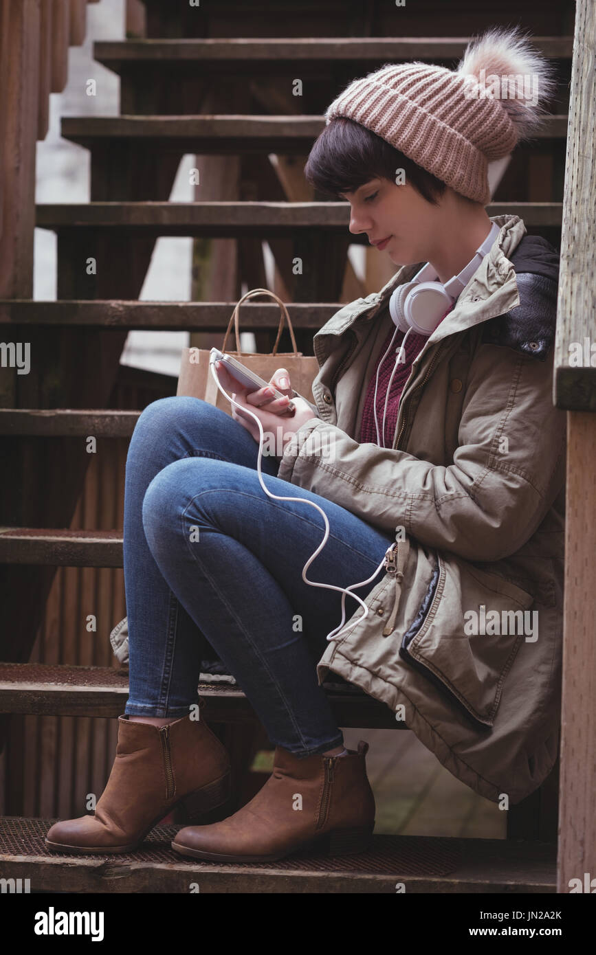 Bella donna usando il cellulare mentre ascolti la musica sulle cuffie Foto Stock