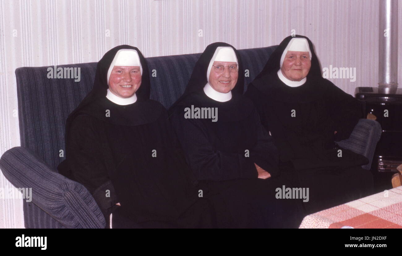 C1973. Tre monache di abitudine seduti sul divano a sorridere alla telecamera. Fotografia di Tony Henshaw Foto Stock