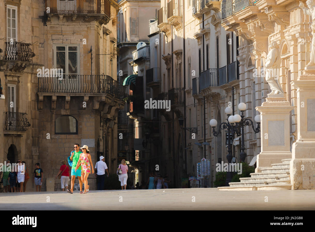 Giovane Italia città, vista di un giovane uomo e donna in vacanza a piedi attraverso una piazza in Ortigia, Sicilia, Italia. Foto Stock