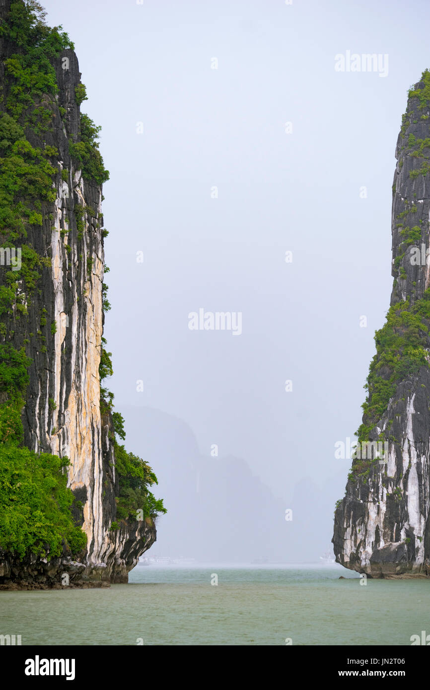 Divario tra due pietre calcaree carsiche su un nebbioso giorno a Halong Bay, Vietnam Foto Stock