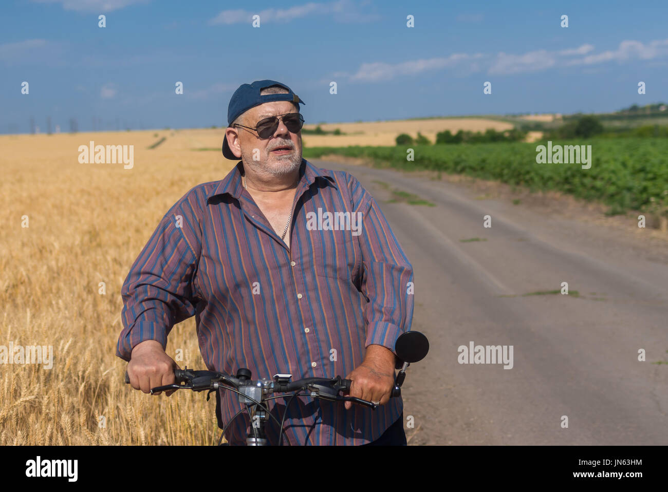 Outdoor ritratto di un barbuto, paffuto uomo senior si prepara per il giro in bicicletta Foto Stock