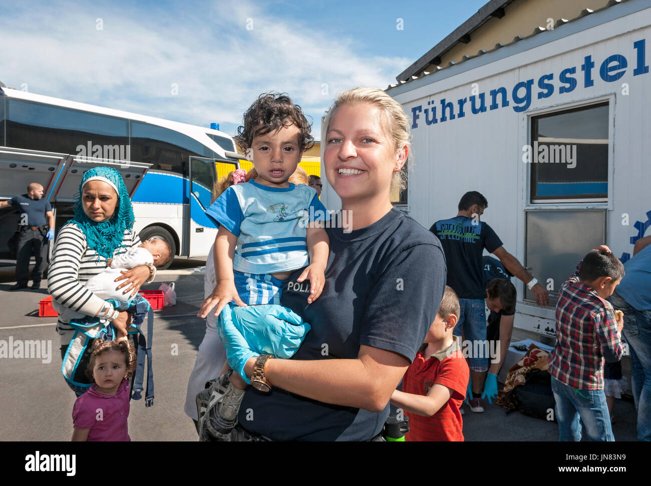 Passau, Germania - 1 Agosto 2015: Una poliziotta tedesco (Juliane Königis) avendo cura di un giovane rifugiato bambino (Ahand) dalla Siria. Foto Stock
