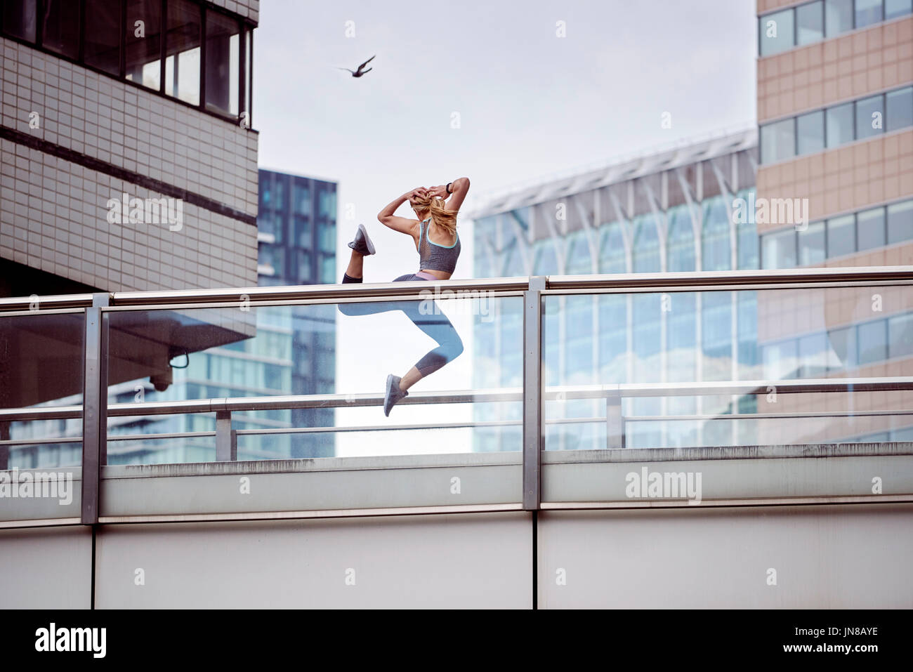 Una giovane donna esprime la sua gioia e libertà saltando in aria in un paesaggio urbano Foto Stock