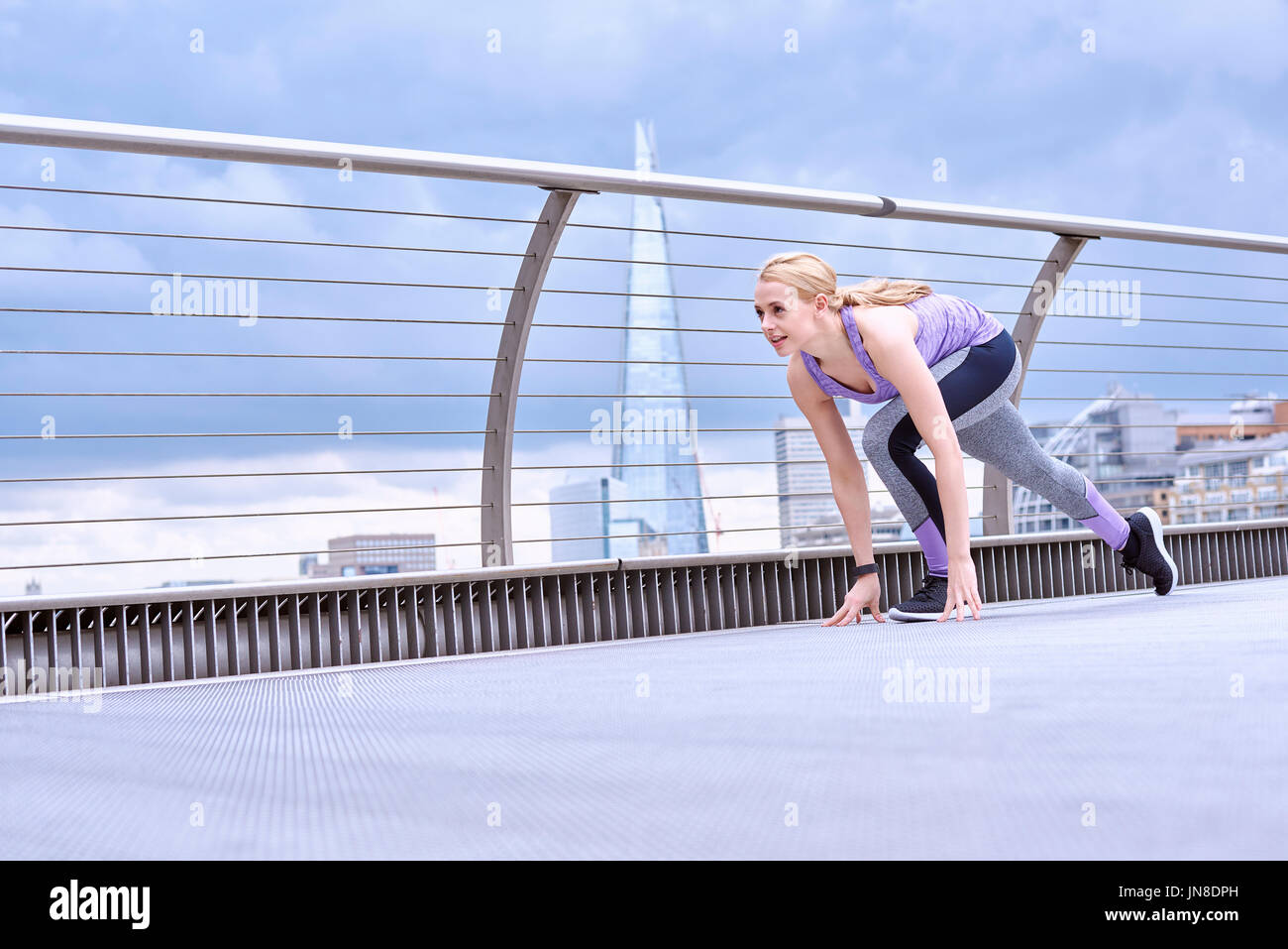 Una giovane donna si prepara a sprint sul Millennium Footbridge Foto Stock