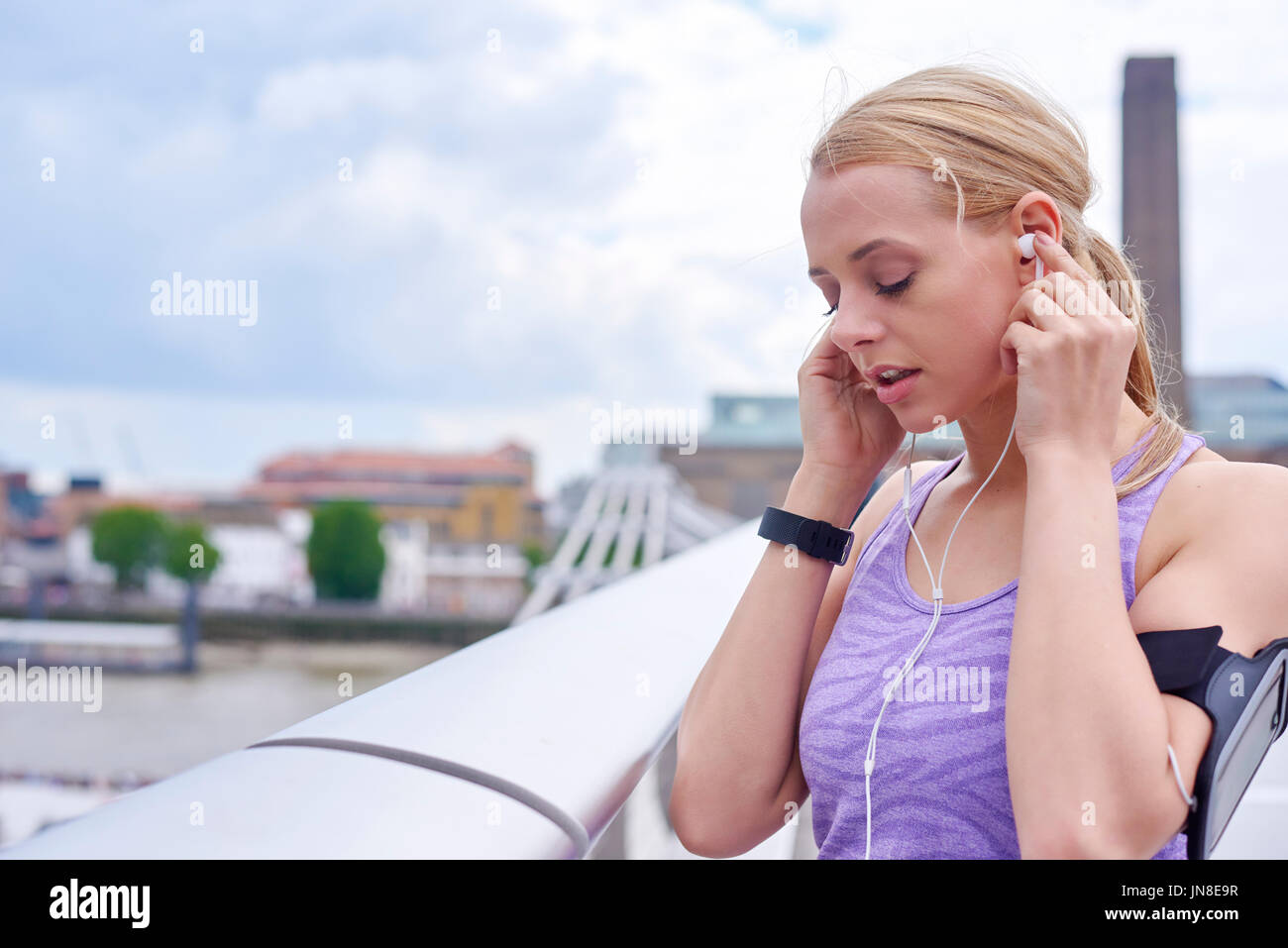 Una giovane donna si ferma per rilassarsi mentre si esercita nella città Foto Stock