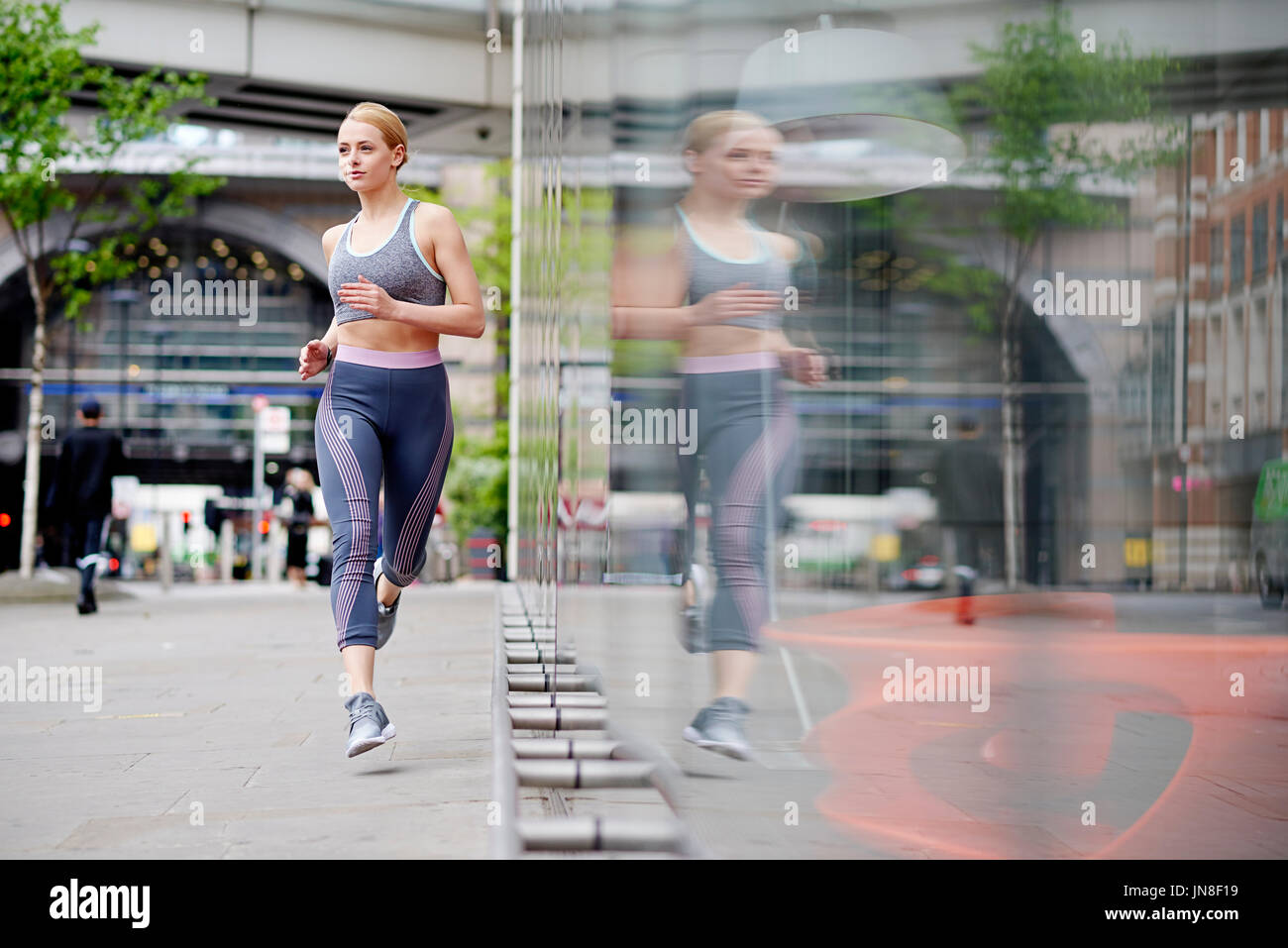 Una giovane donna corre in città Foto Stock