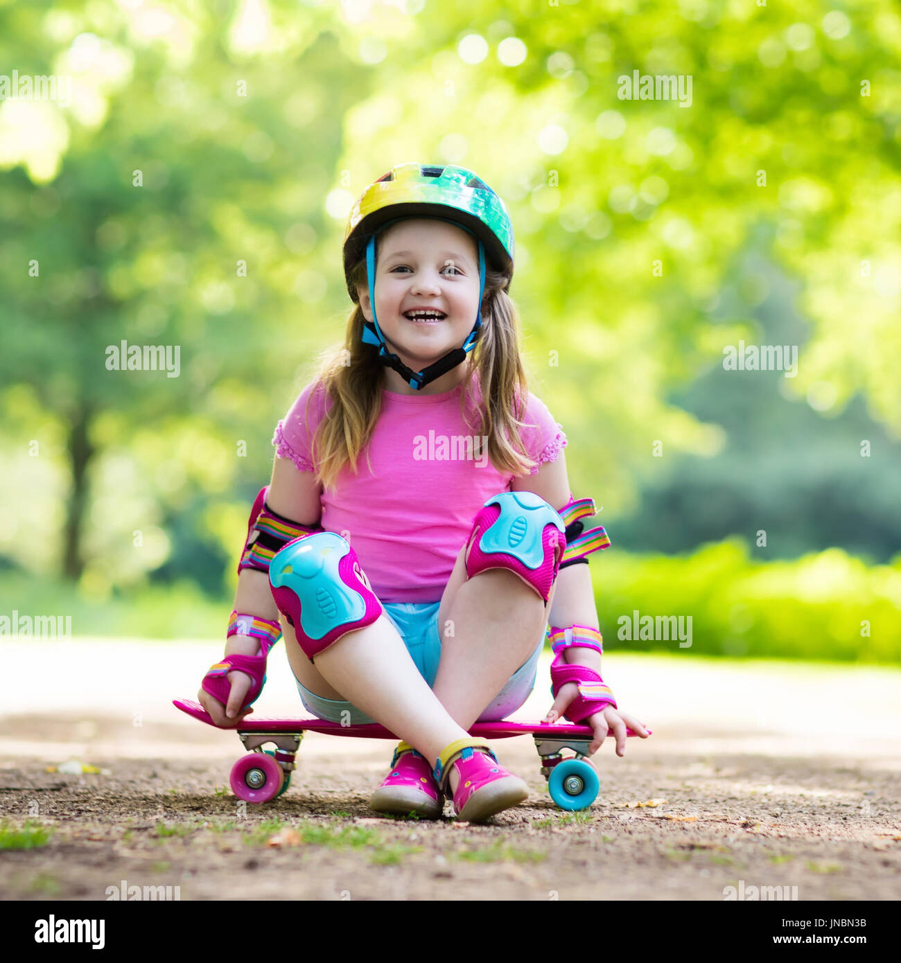 Equitazione per bambini skateboard in estate park. Bambina di imparare a cavalcare skateboard. Active outdoor sport per la scuola e per la scuola materna i bambini. Bambini skat Foto Stock