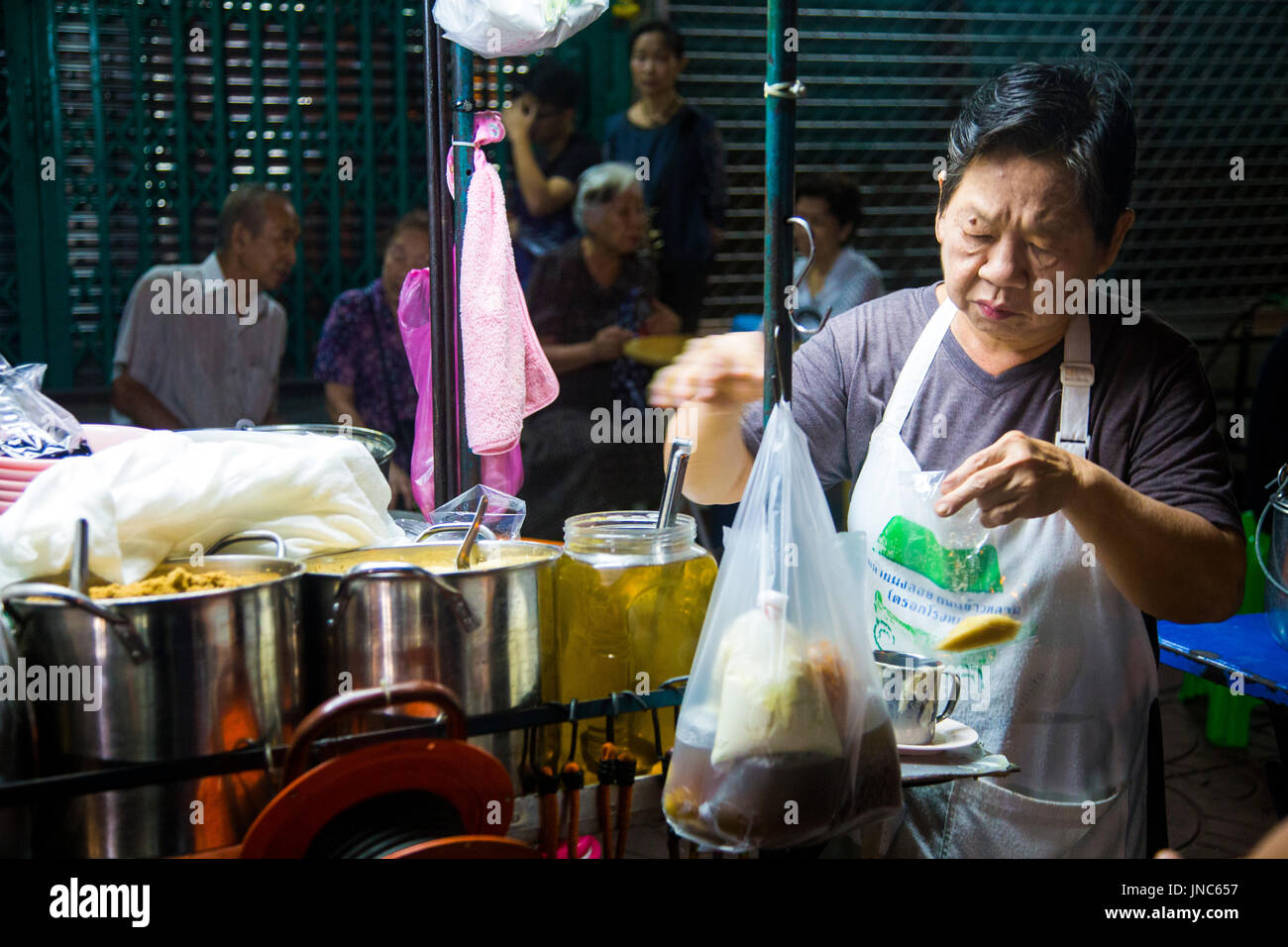 Uomo Tailandese prepara il cibo in una fase di stallo notte mercato alimentare a Chinatown, Bangkok, Thailandia Foto Stock