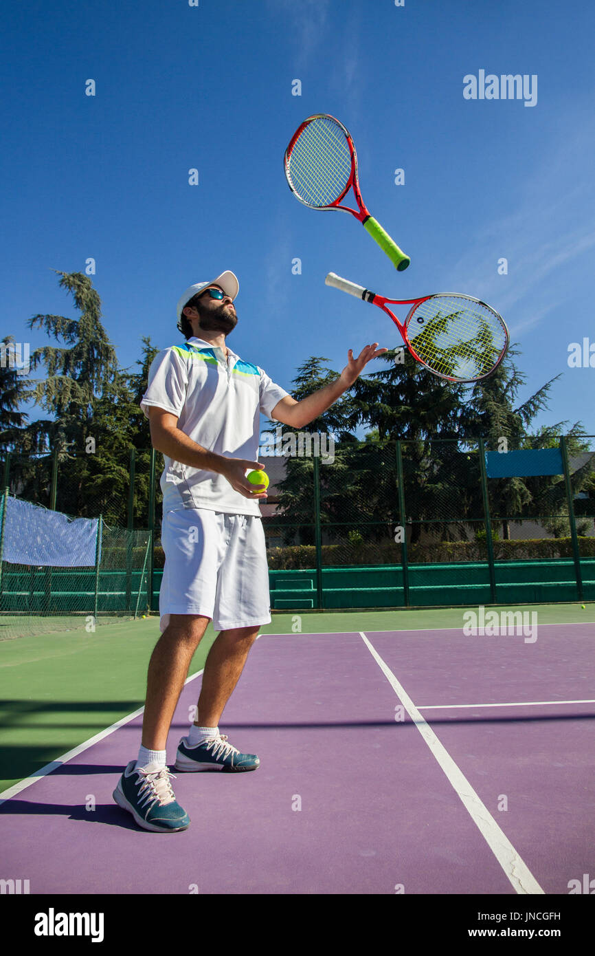 Giocatore di tennis professionista giocoleria con racchette. Egli è di avere un buon tempo prima di iniziare il gioco. Foto Stock