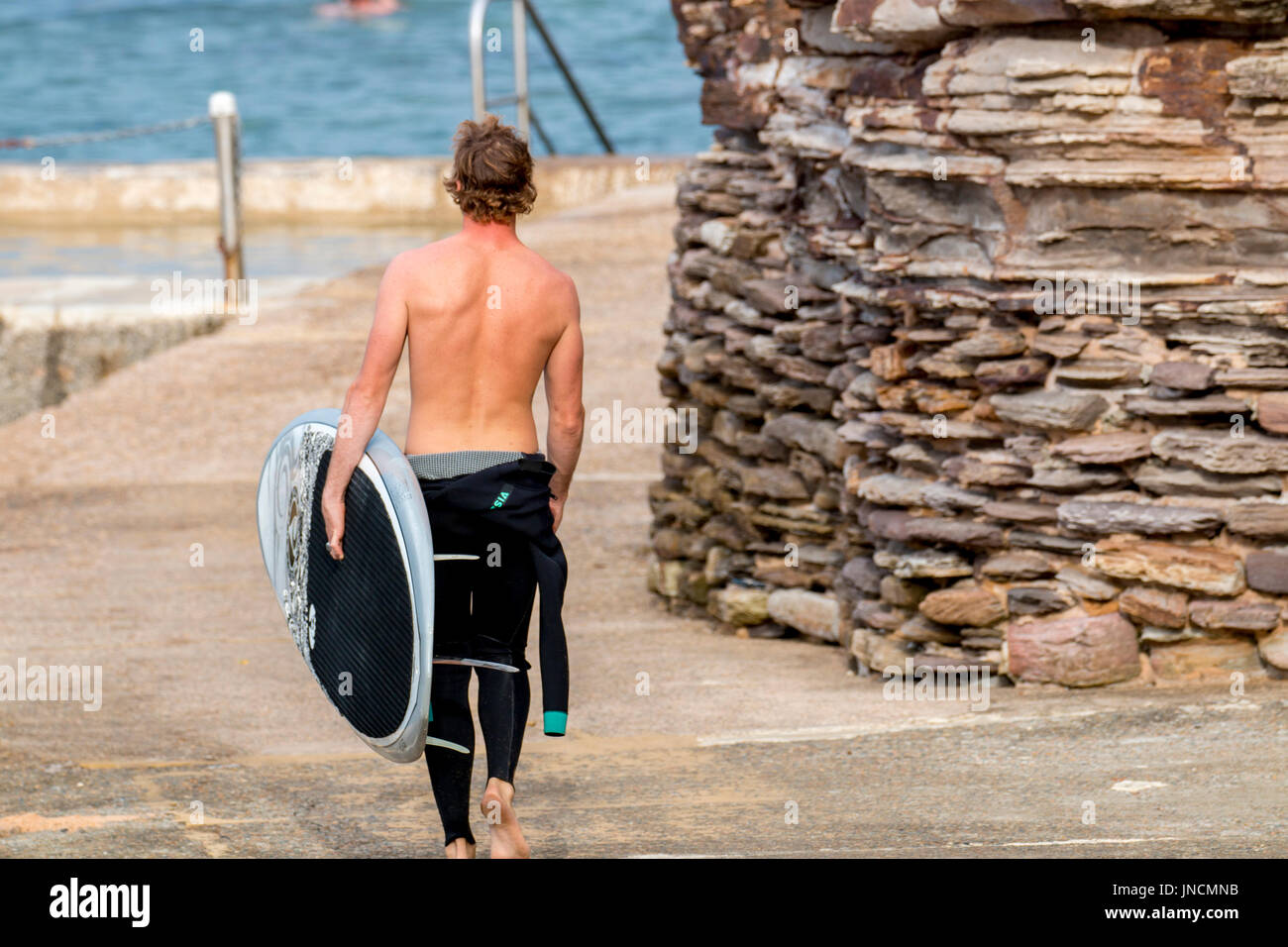 Il giovane australiano adolescente di sesso maschile portando la sua tavola da surf per il surf a Avalon Beach,Sydney , Australia Foto Stock