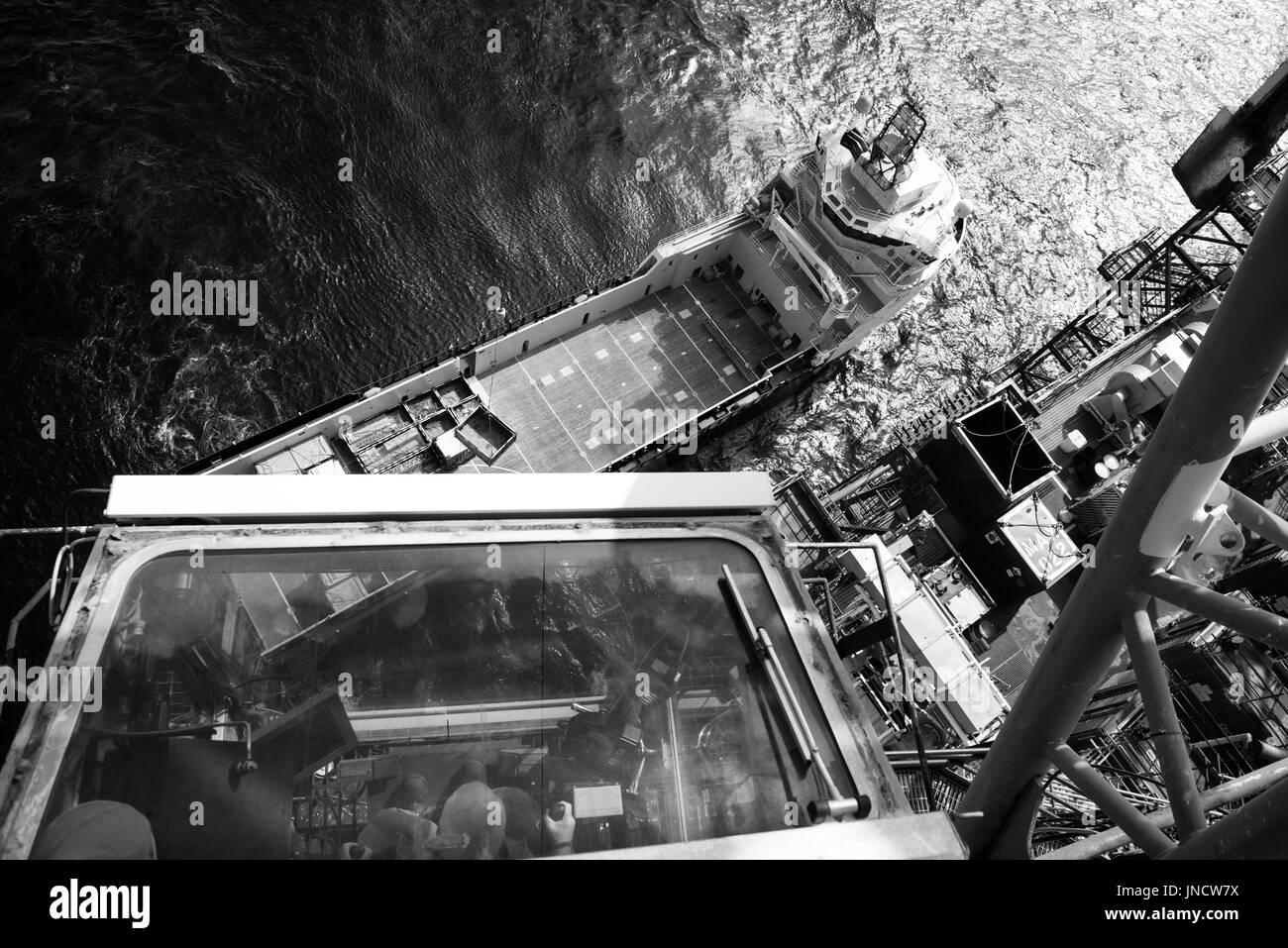 Immagine in bianco e nero di un mare del Nord nel settore petrolifero e del gas naturale, gru decollare le forniture dal recipiente di alimentazione. Credito: lee ramsden / alamy Foto Stock