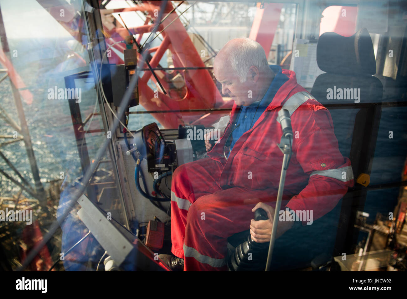 Un operatore di gru (driver) lavorando la sua gru scaricando il carico di contenitori a partire da un recipiente di alimentazione. Credito: lee ramsden / alamy Foto Stock