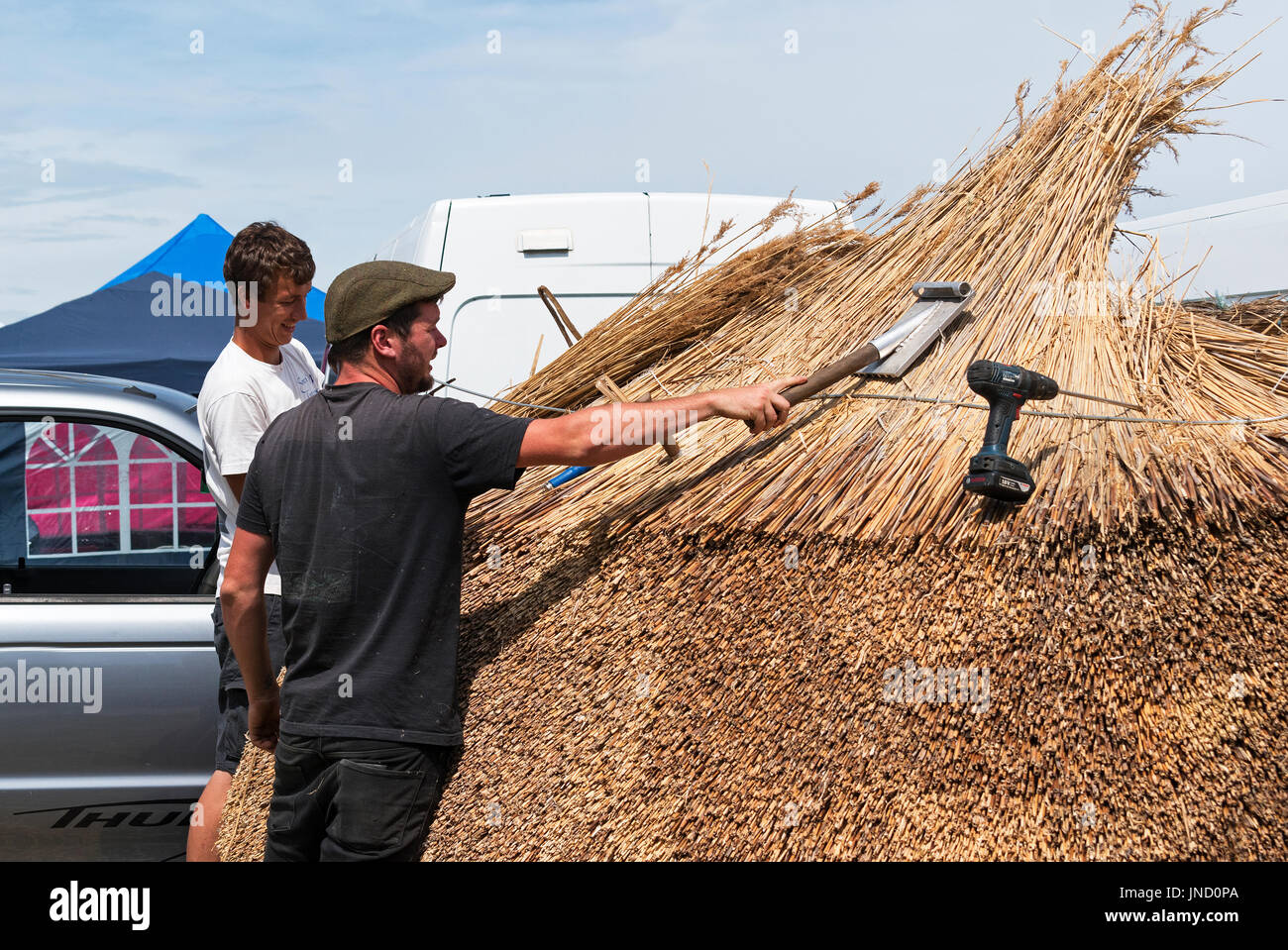 Thatchers tetto dando una mostra di lattoneria le competenze necessarie a una fiera di paese in Cornovaglia, Inghilterra, Regno Unito. Foto Stock