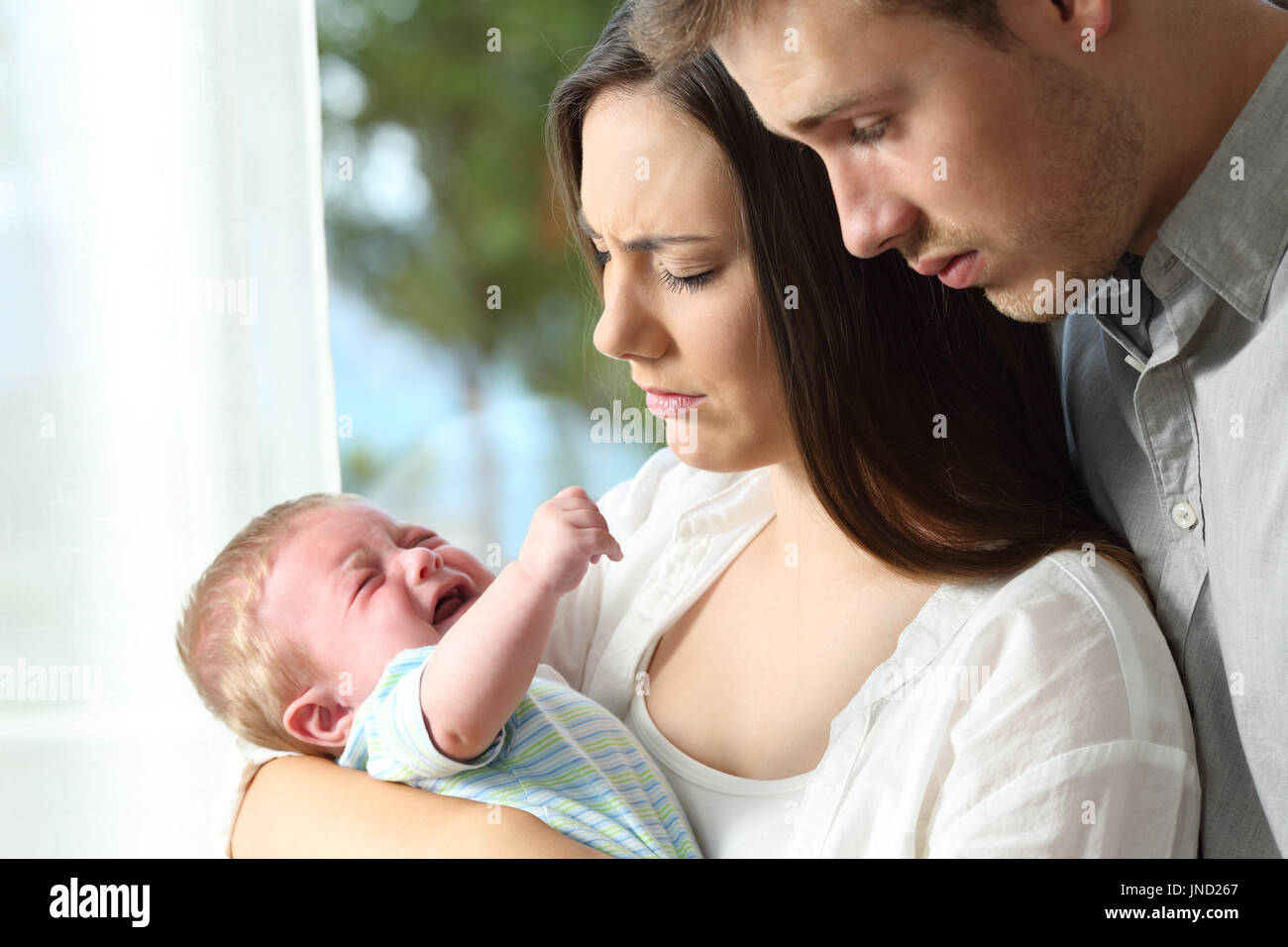 Stanchi genitori disperati tenendo il loro bambino piange disperatamente a casa Foto Stock