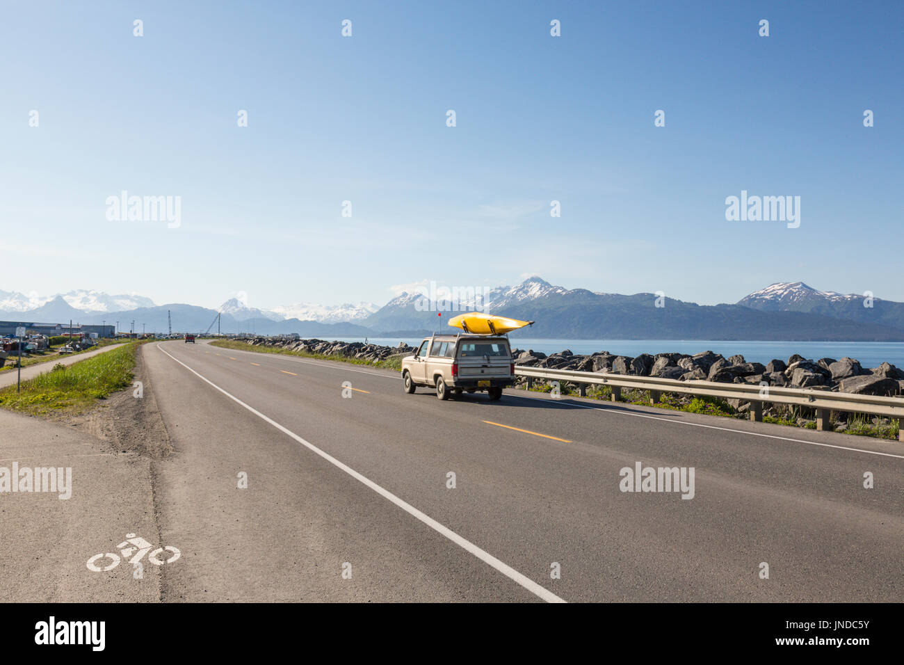 Auto con il kayak sul tetto aziona lungo Homer Spit, Omero, Alaska, STATI UNITI D'AMERICA Foto Stock