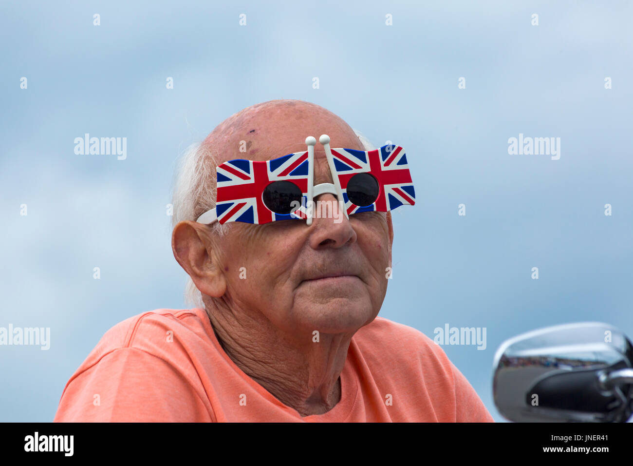 Swanage, Dorset, Regno Unito. Il 30 luglio, 2017. I visitatori accorrono a Swanage per guardare la processione parade, come parte di Swanage la settimana di carnevale. Il tema di quest anno è Swanage diventa globale per i partecipanti per mostrare il vestito nazionale o le caratteristiche del loro paese preferito. Uomo che indossa la novità di Union Jack Flag bicchieri prende parte alla sfilata di carnevale. Credito: Carolyn Jenkins/Alamy Live News Foto Stock