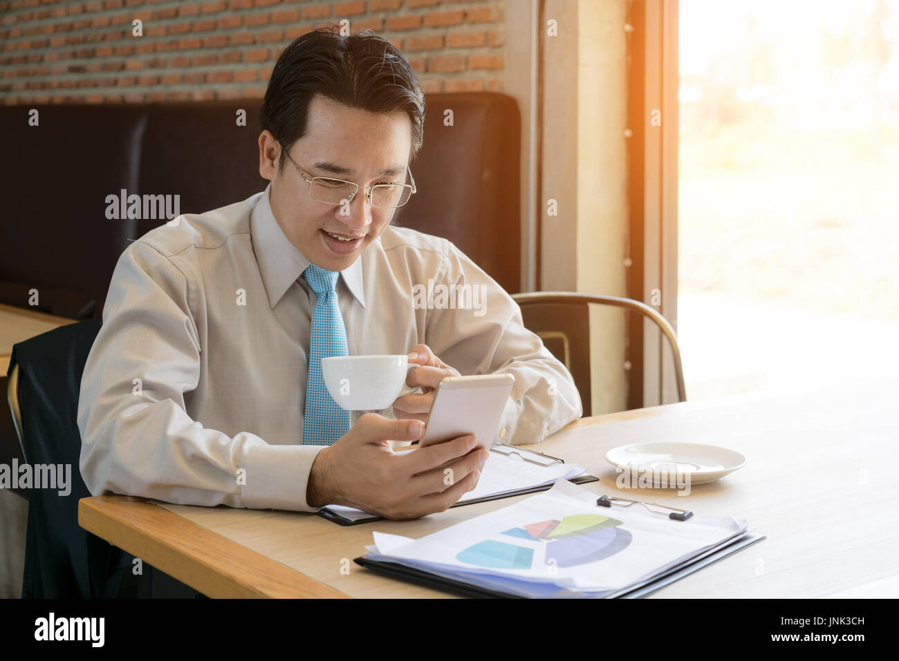 Imprenditore boss in camicia casual per il controllo della posta elettronica tramite cellulare prima di un incontro con il personale. Maschio di datore di lavoro professionale è la digitazione di un messaggio di testo sul cellulare Foto Stock