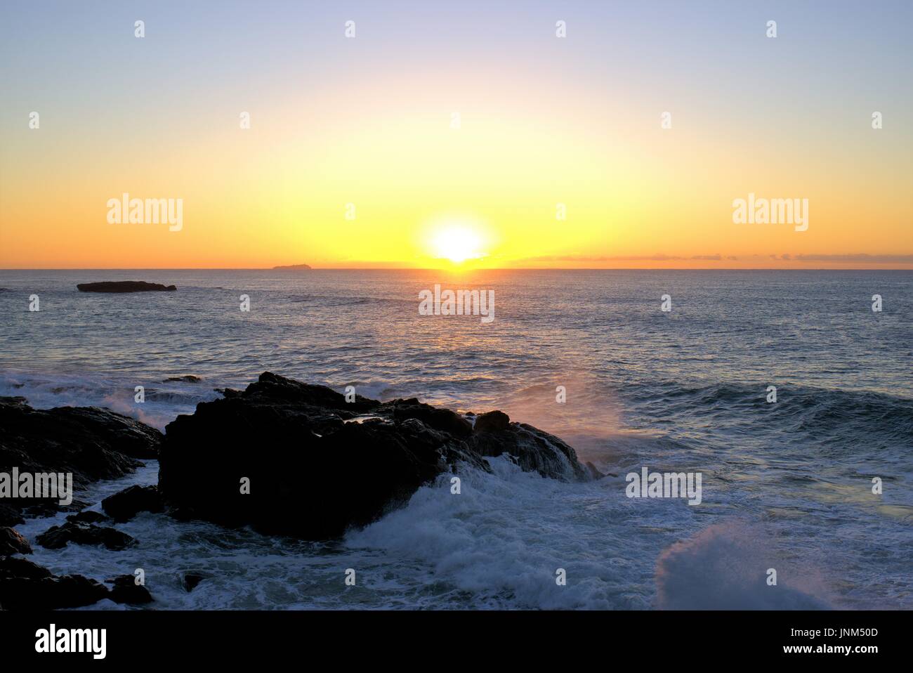 Beach Sunrise onde di colpire le rocce. La mattina presto a sunrise costa con rocce. Foto Stock