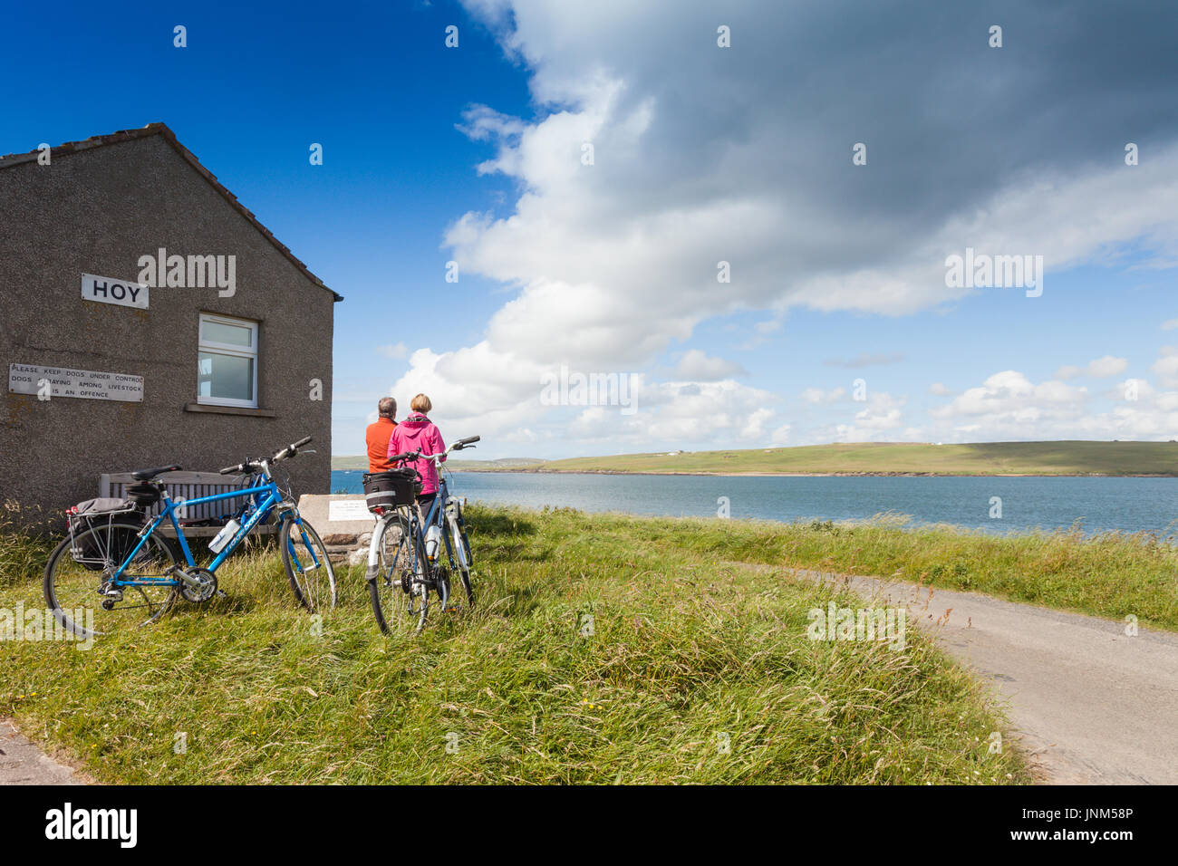 Due ciclisti in attesa per il traghetto da Hoy in terraferma Orkney, REGNO UNITO Foto Stock