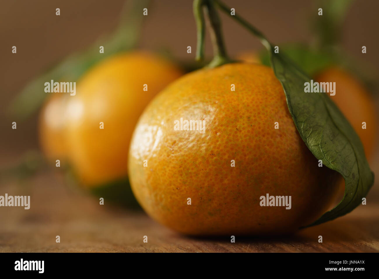 Tangerini organico con foglie sulla tavola di legno Foto Stock