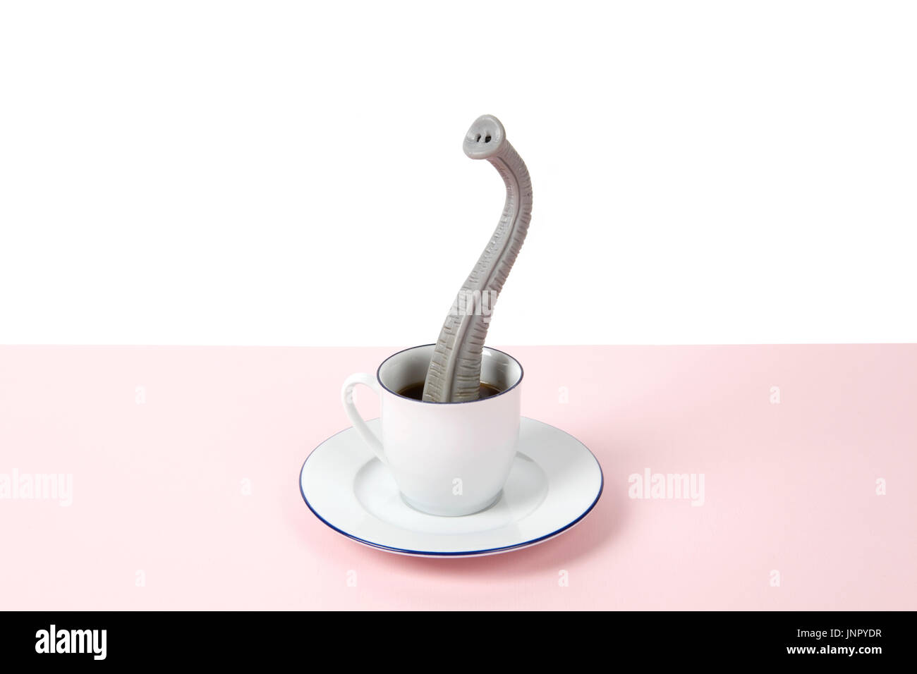 Una proboscide emergente da un design di piccole dimensioni tazza di caffè come se egli fosse nascosto. Il minimo divertente e stravagante design vita ancora fotografia Foto Stock