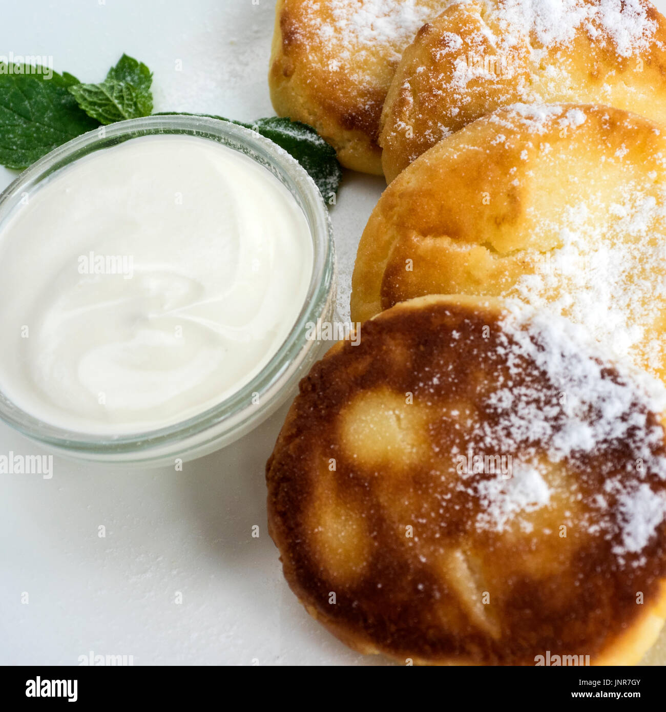 Frittelle di cagliata e panna acida su un tavolo Foto Stock