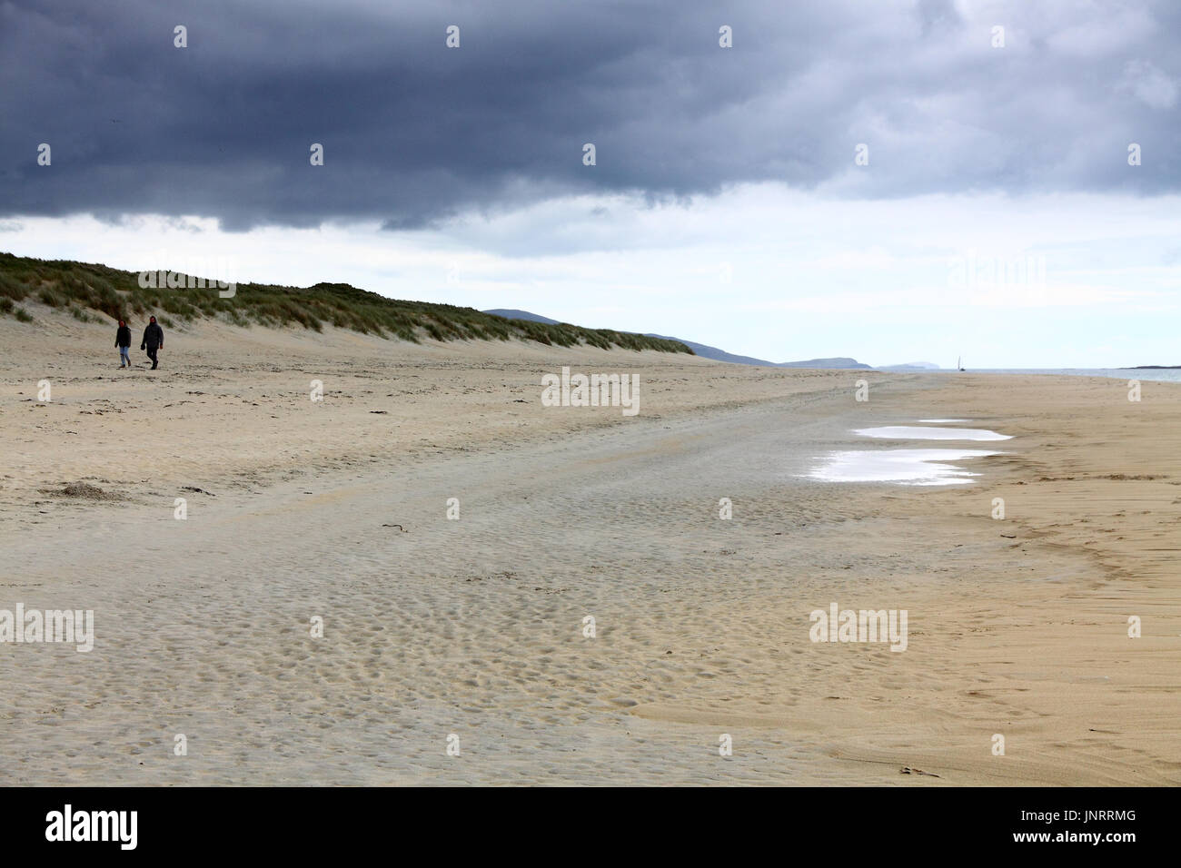 Giovane camminando sulla spiaggia Luskentire, Isle of Harris e Lewis, Scozia su un nuvoloso giorno Foto Stock