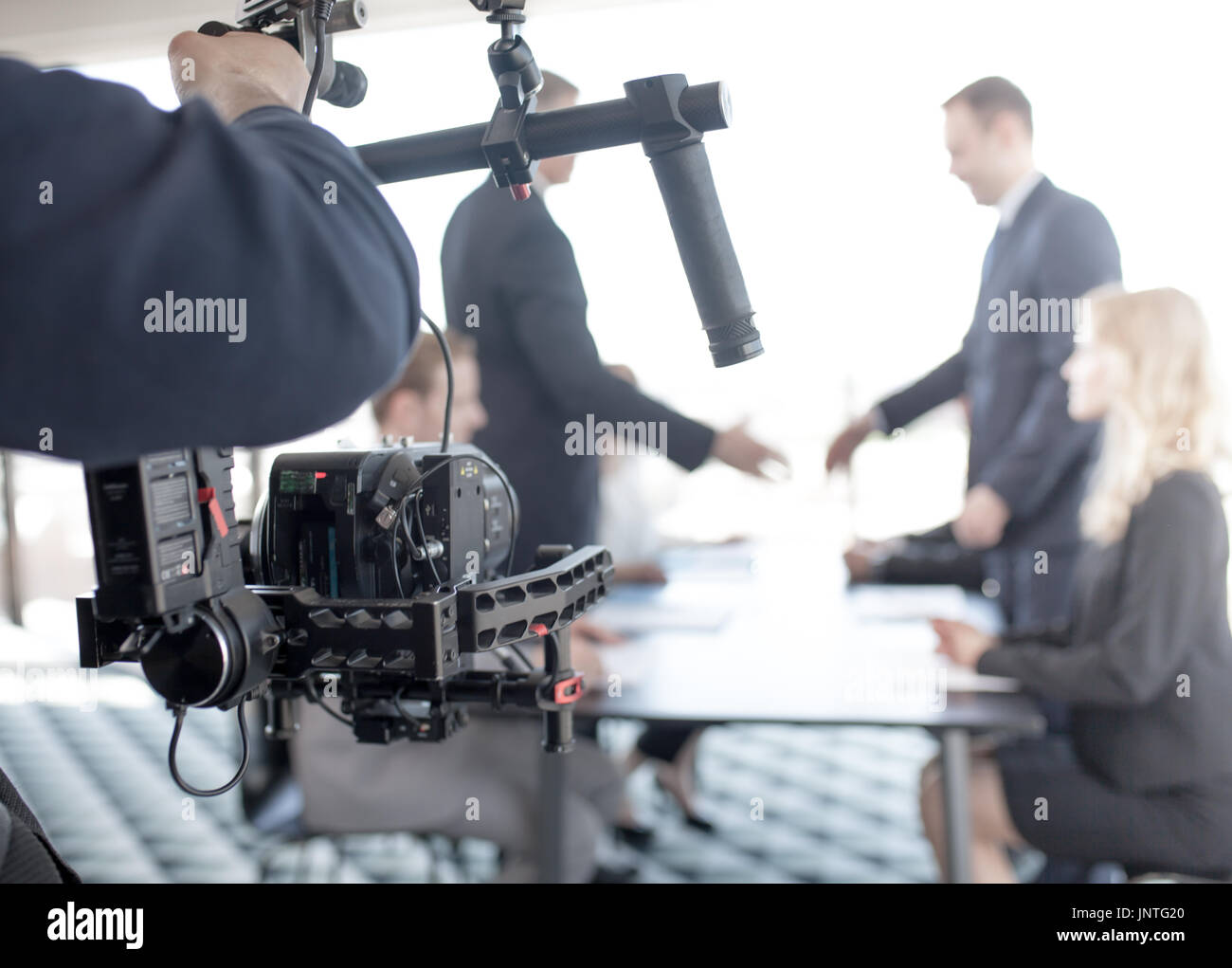 Videografo utilizzando steadicam, rendendo il video di uomini di affari che stringono le mani Foto Stock