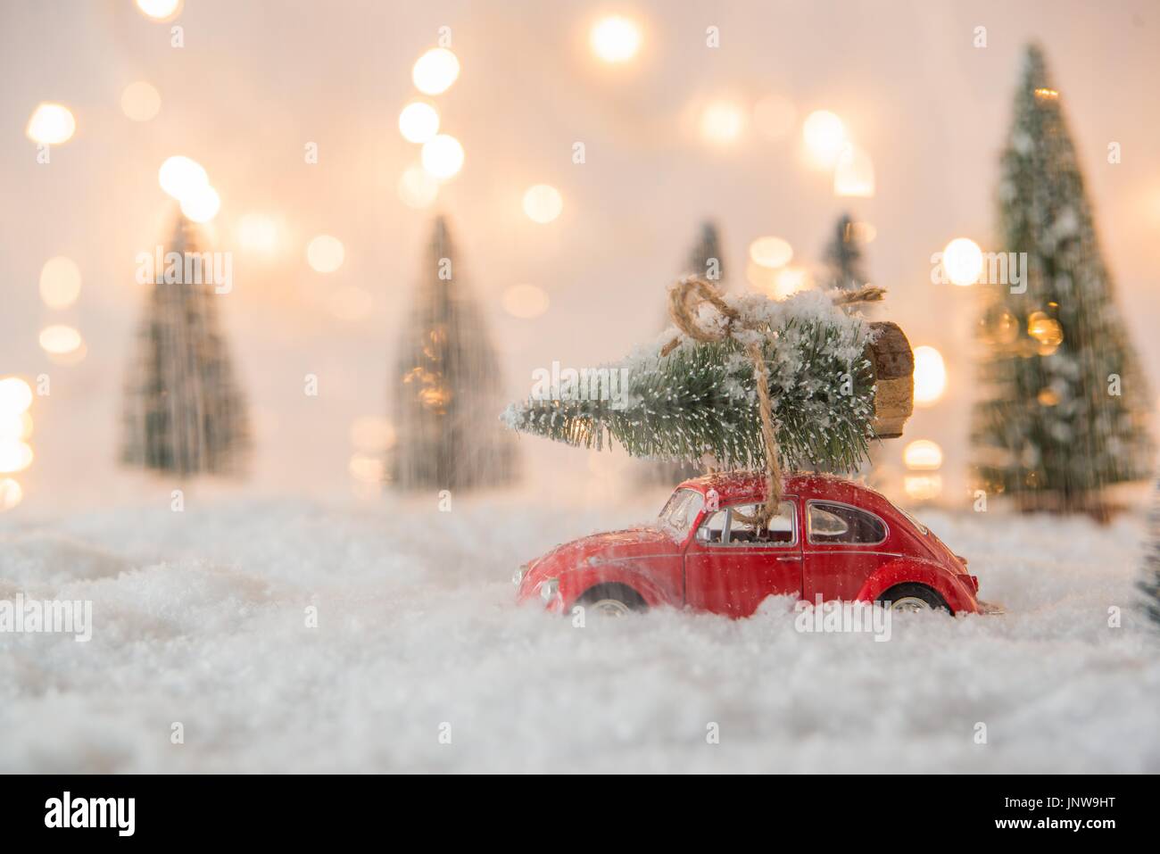 Little Red auto giocattolo che porta l'albero di Natale in coperta di neve la foresta in miniatura Foto Stock
