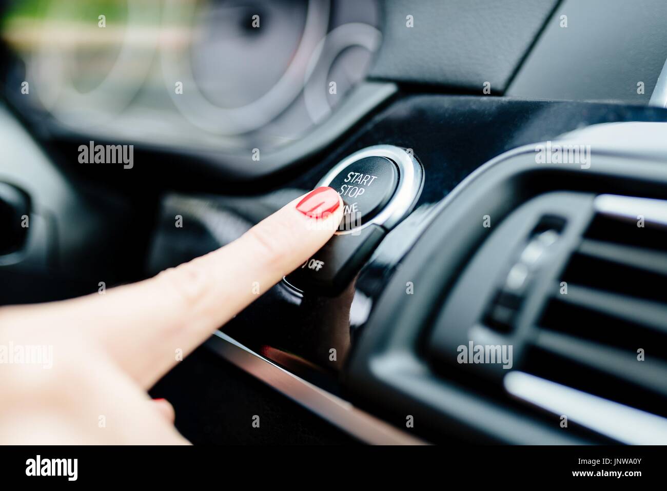 La donna si avvia il motore dell'auto con start-stop pulsante. Auto moderna interno Foto Stock