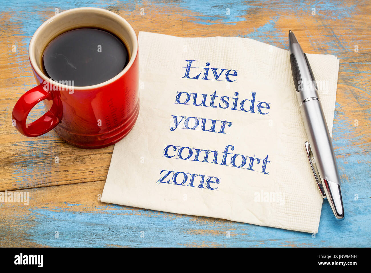 Vivere al di fuori della propria zona di comfort - grafia di ispirazione su un tovagliolo con una tazza di caffè Foto Stock