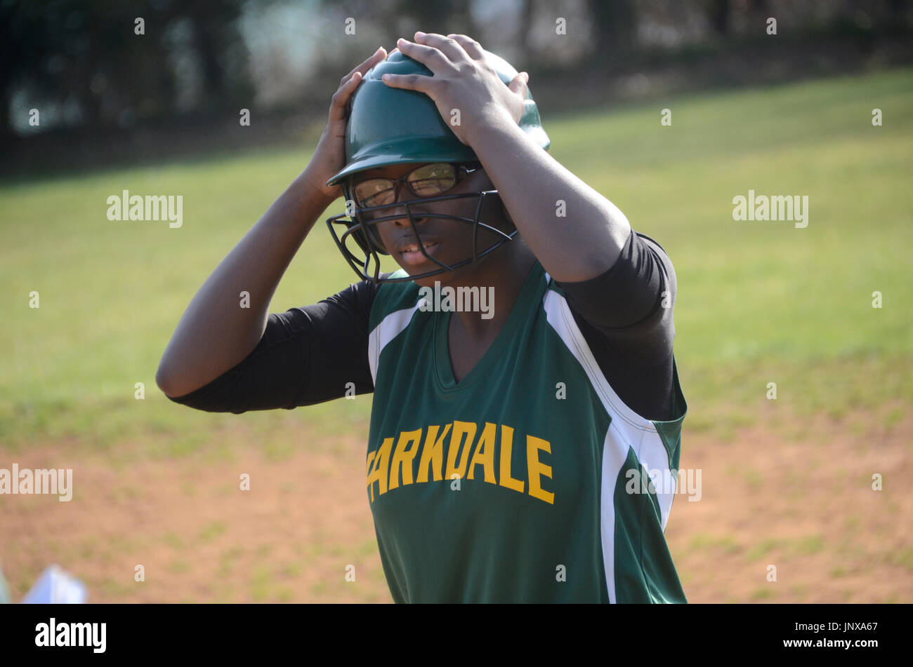 Un softballplayer regolare il suo casco di ovatta durante una high school softball game Foto Stock