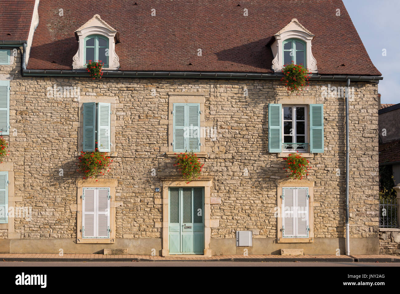 Beaune, Borgogna, Francia - 11 Ottobre 2015: casa in pietra con un pallido persiane verdi e rossi gerani in scatole di finestra, Beaune, Borgogna, Francia Foto Stock